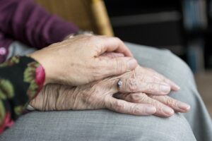Die Hände von zwei älteren Frauen liegen aufeinander.